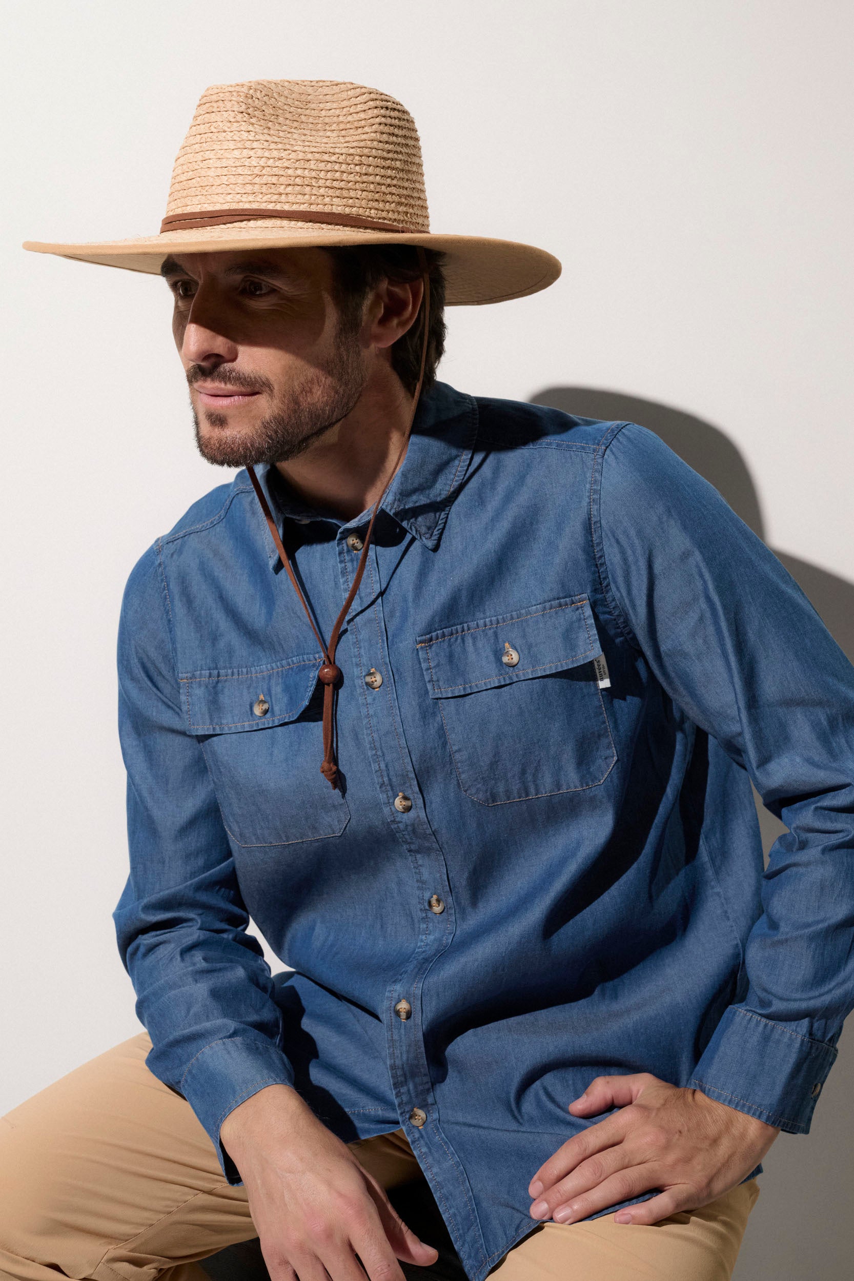 Homme portant un chapeau anti-UV en paille et une chemise en denim, idéal pour une protection solaire UPF50+.