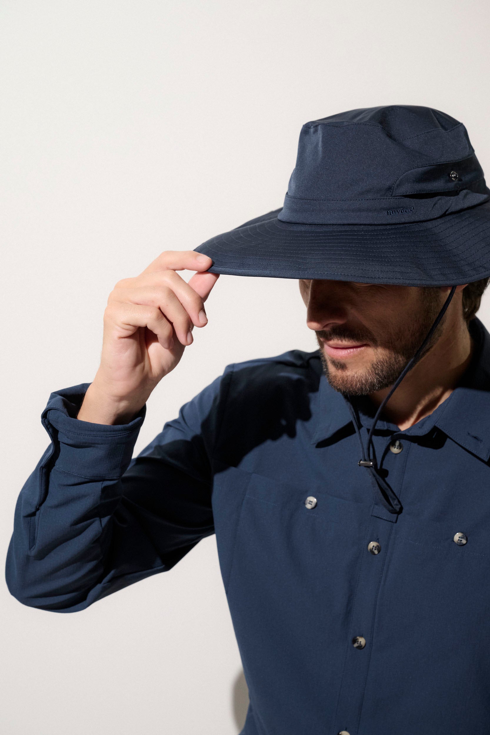Homme portant un chapeau anti-UV bleu UPF50+, idéal pour la randonnée en plein air et la protection solaire.