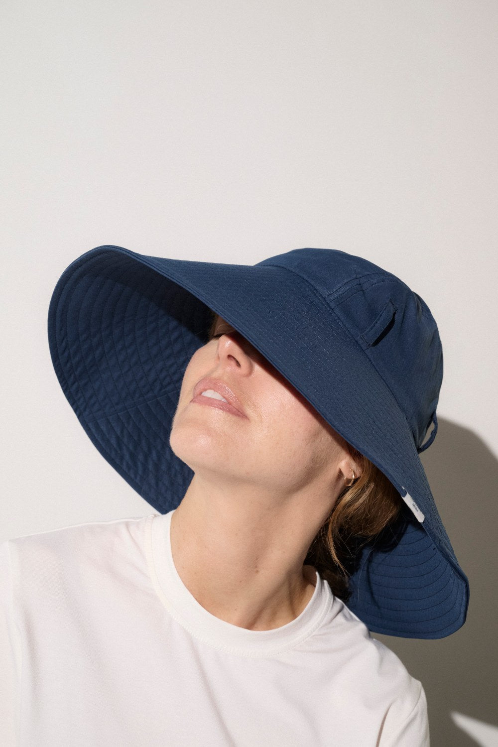 Chapeau anti-UV bleu pour femme, offrant une protection solaire avec un large bord et une jugulaire ajustable.