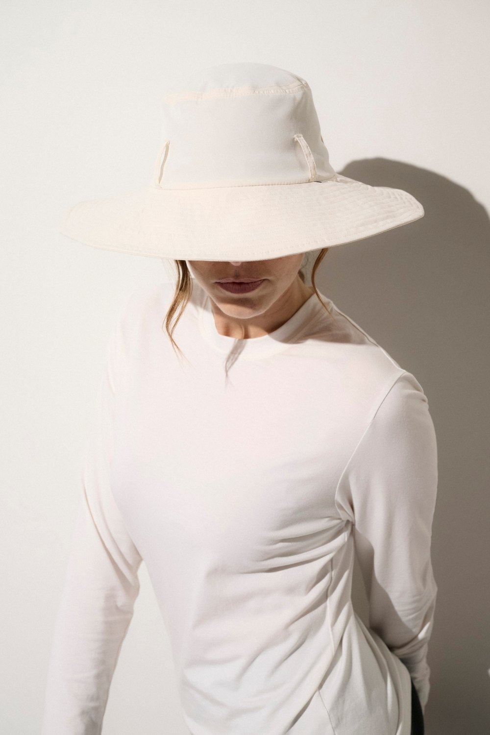 Chapeau anti-UV blanc UPF 50+ porté par une femme, idéal pour une protection solaire élégante au quotidien.