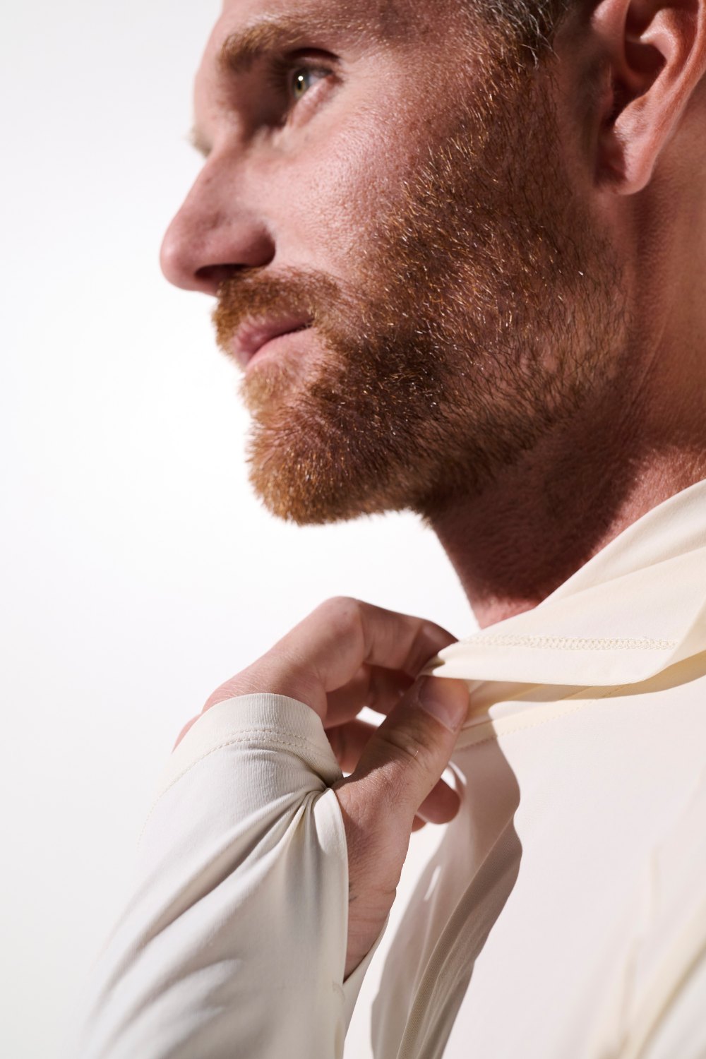 Homme ajustant son t-shirt anti-UV à capuche - Oasis, en tissu léger, UPF 50+, idéal pour le sport.