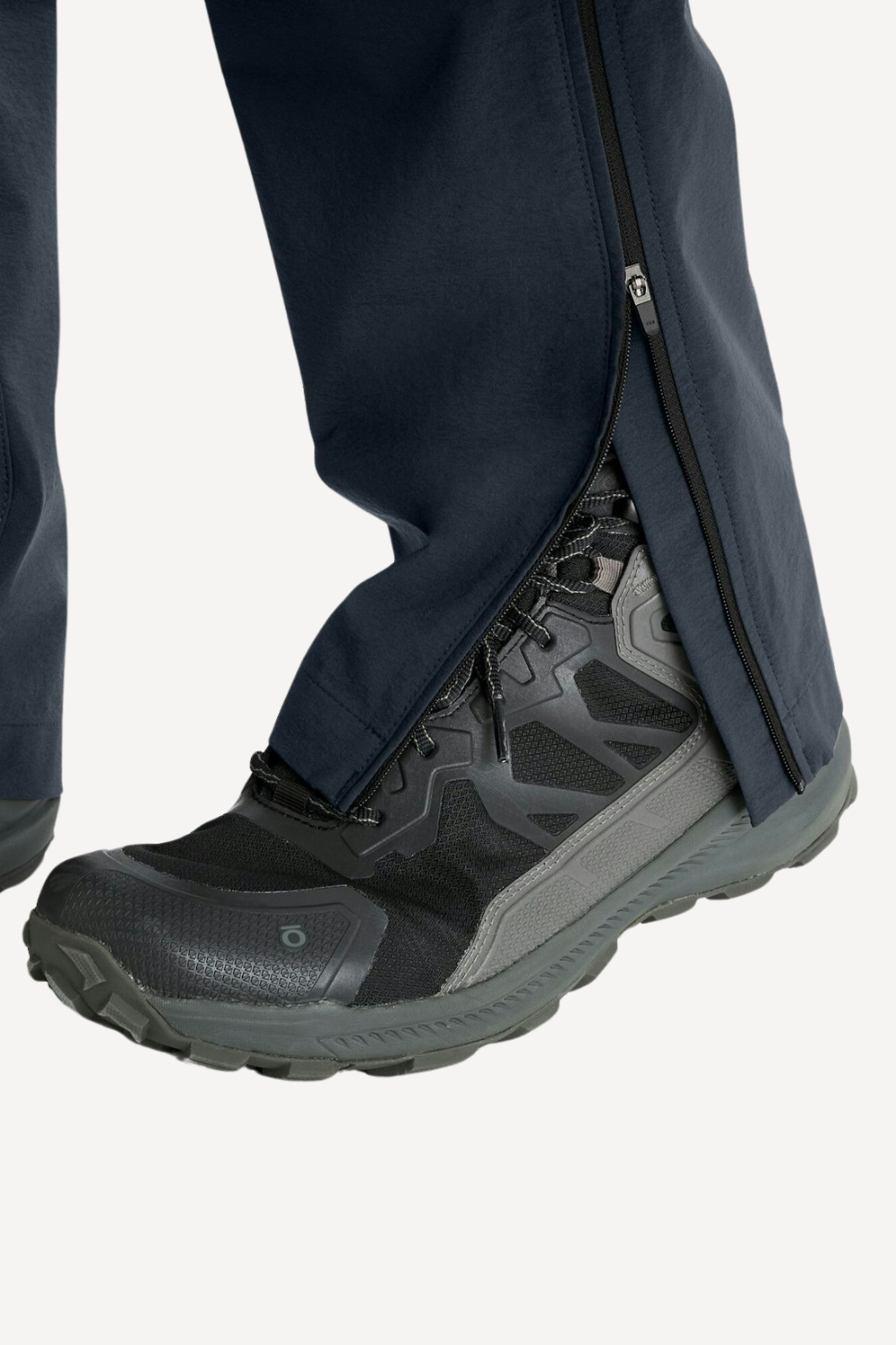 Pantalon de voyage léger et confortable avec fermeture éclair, porté avec des chaussures de randonnée, idéal pour l'extérieur.