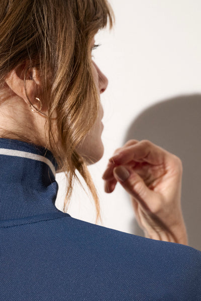 Femme portant un polo anti-UV bleu foncé, élégant, avec col, offrant protection solaire UPF50+.