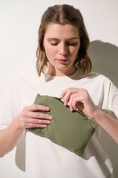 Femme ouvrant une pochette légère verte, pratique et fonctionnelle, idéale pour les sorties en plein air.