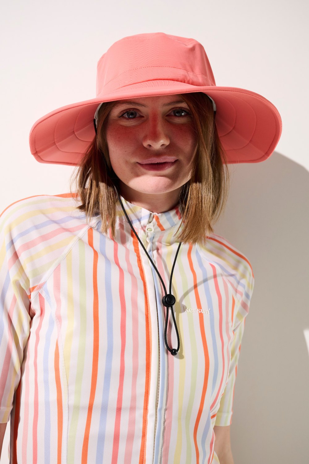 Chapeau de bain anti-UV - Galápagos en rose porté par une femme, léger et confortable pour la protection solaire.