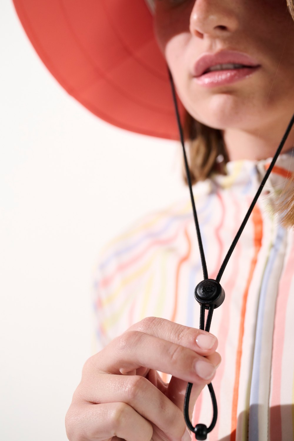 Chapeau de bain anti-UV - Galápagos en rouge porté par une femme, offrant protection solaire UPF 50+.