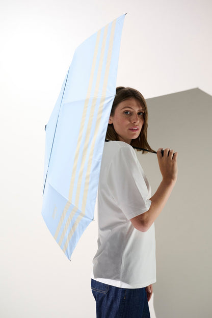 Ombrelle anti-UV femme bleue avec rayures, protection solaire UPF 50+, sous un soleil radieux.