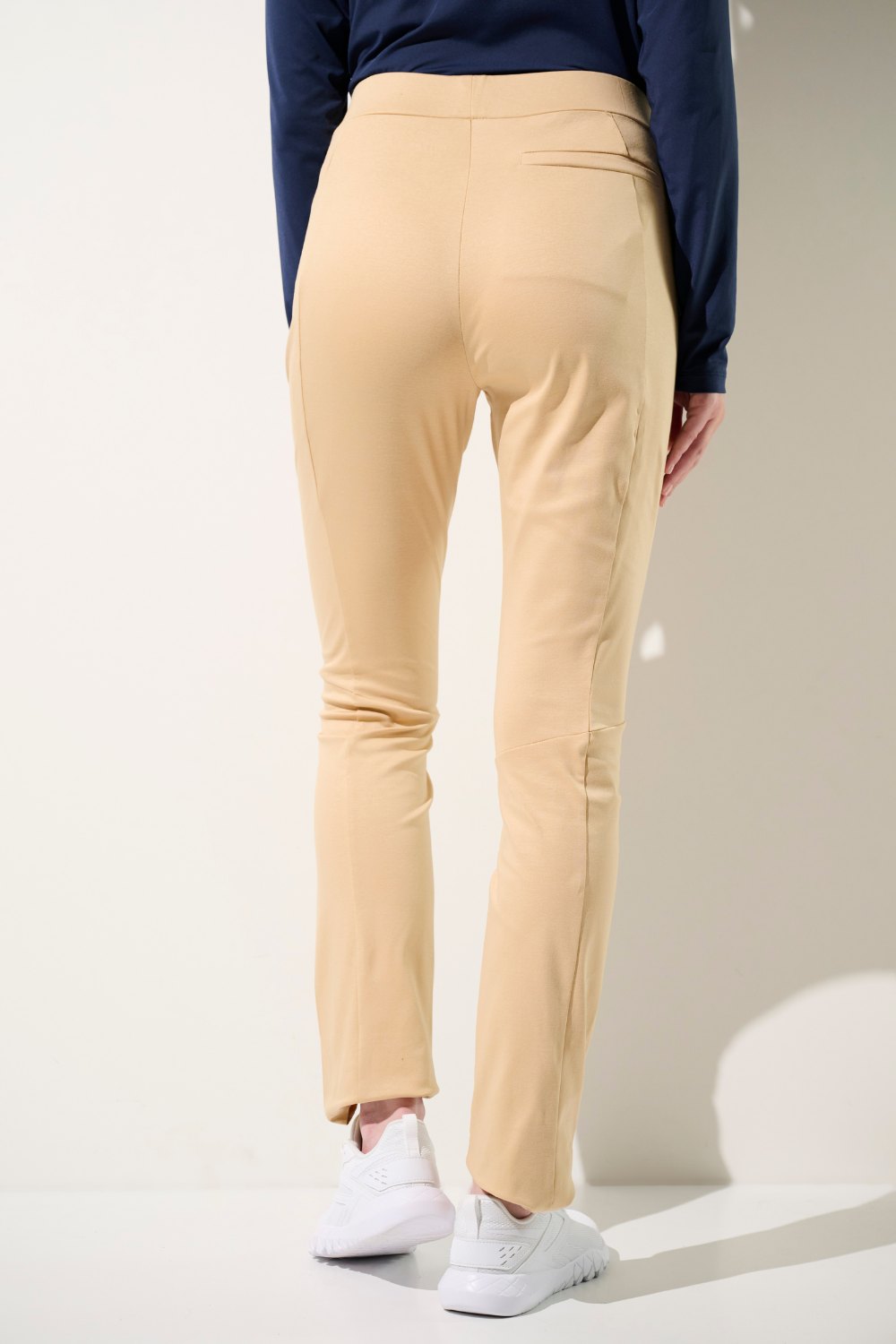 Femme vue de dos, portant un pantalon anti-UV beige clair idéal pour protéger sa peau du soleil sans contrainte.