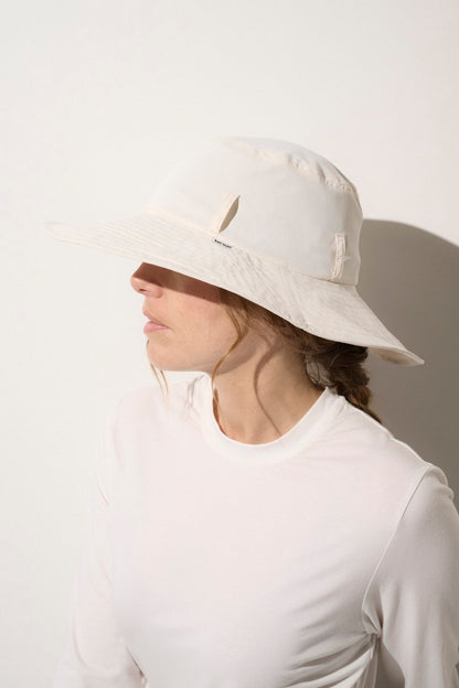 Chapeau anti-UV blanc UPF 50+ porté par une femme, léger et élégant pour une protection solaire quotidienne.
