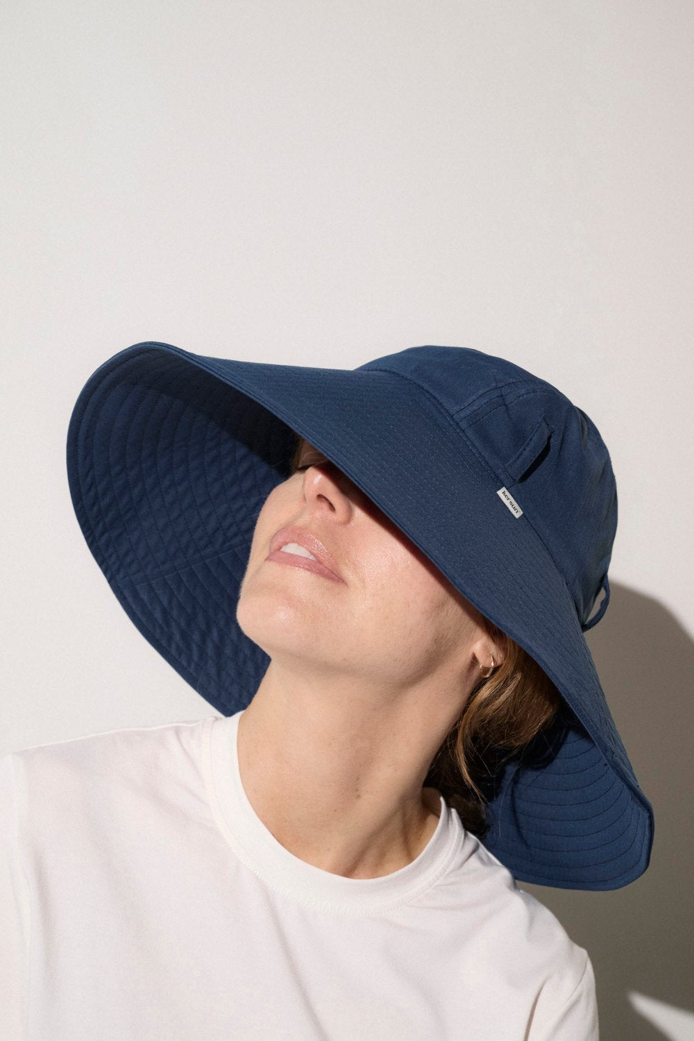 Chapeau anti-UV bleu pour femme, offrant une protection solaire avec un large bord et une jugulaire ajustable.