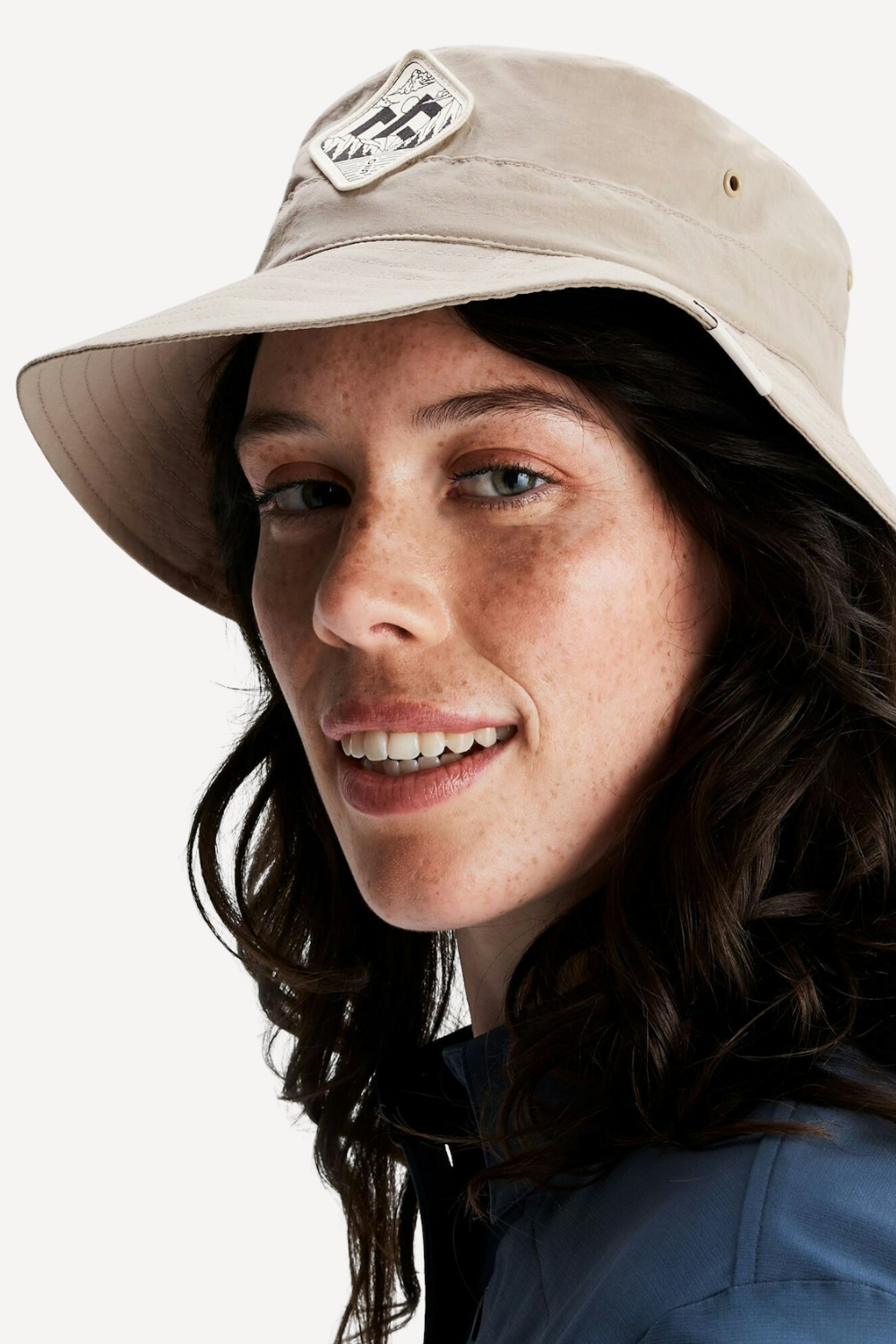 Femme portant un chapeau anti-UV beige, UPF 50+, idéal pour des journées ensoleillées en extérieur.