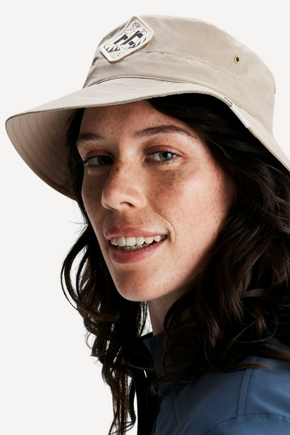 Femme portant un chapeau anti-UV beige, UPF 50+, idéal pour des journées ensoleillées en extérieur.