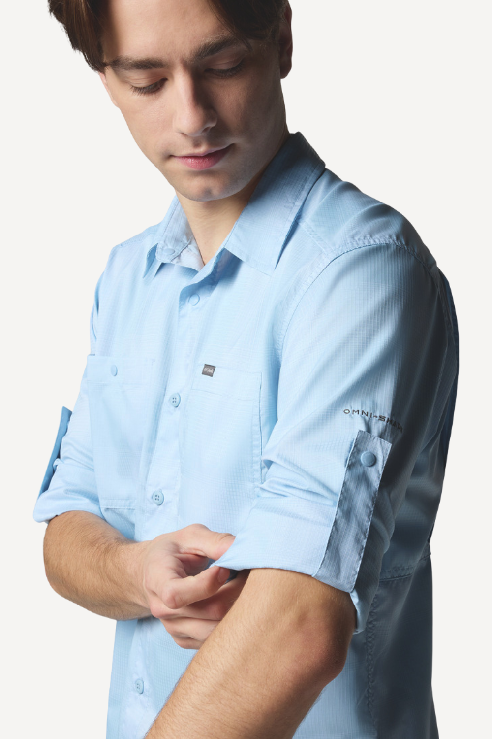 Homme portant une chemise légère anti-UV Columbia, UPF50+, couleur bleu clair, idéale pour activités en plein air.
