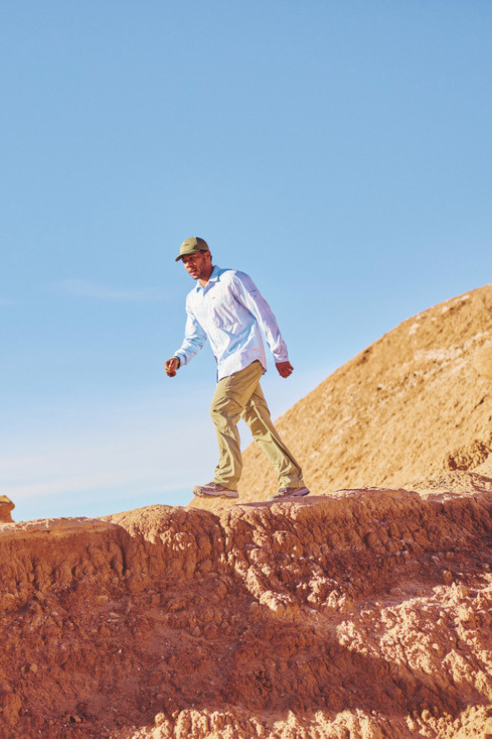 Homme portant une chemise anti-UV Columbia UPF50+, marchant sur un terrain rocheux au soleil.