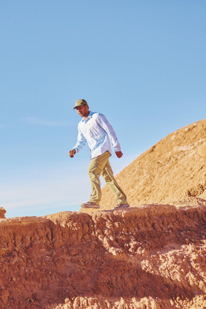 Homme portant une chemise anti-UV Columbia UPF50+, marchant sur un terrain rocheux au soleil.