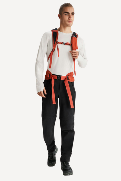 Homme portant un pantalon anti-UV noir et un sweat à manches longues, équipé d'un harnais de randonnée.