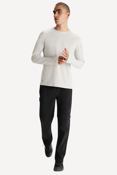 Homme portant un t-shirt anti-UV blanc UPF 50+ et un pantalon noir, parfait pour les activités de plein air.